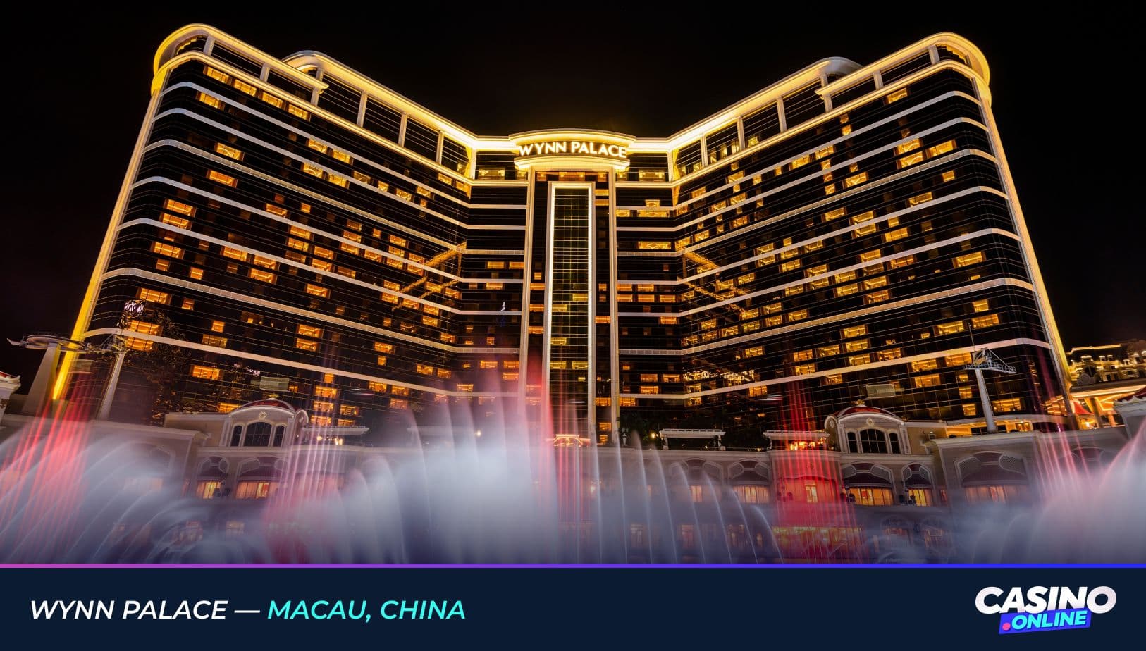 Night view of Wynn Palace in Macau, China, featuring the illuminated hotel facade and vibrant dancing fountain display in the foreground.