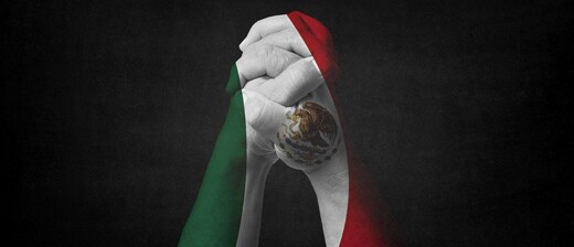 Hands clutched together painted in the colours of the Mexican flag.